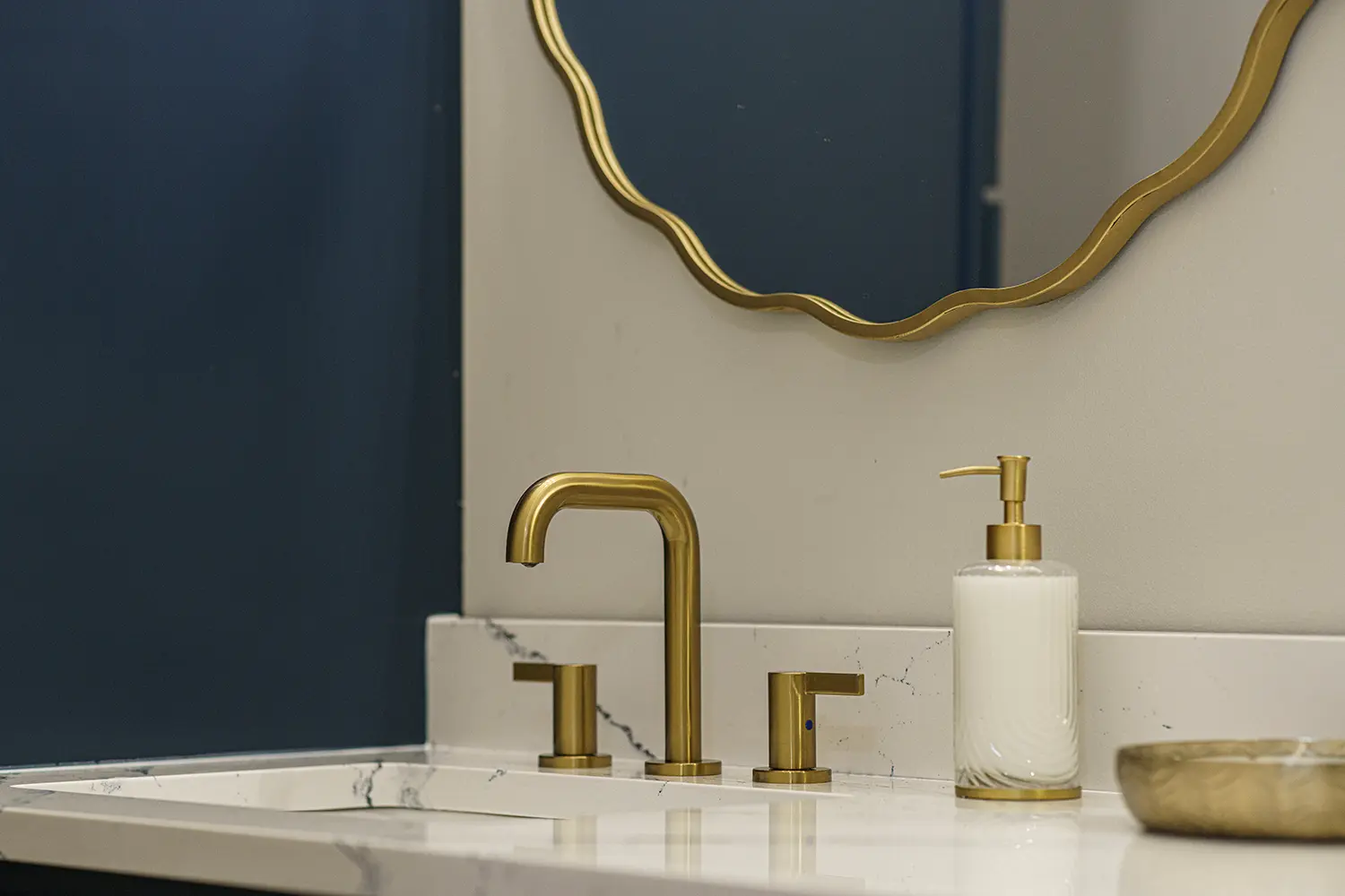 Close-up of a finished bathroom sink with gold faucet and a scalloped backsplash