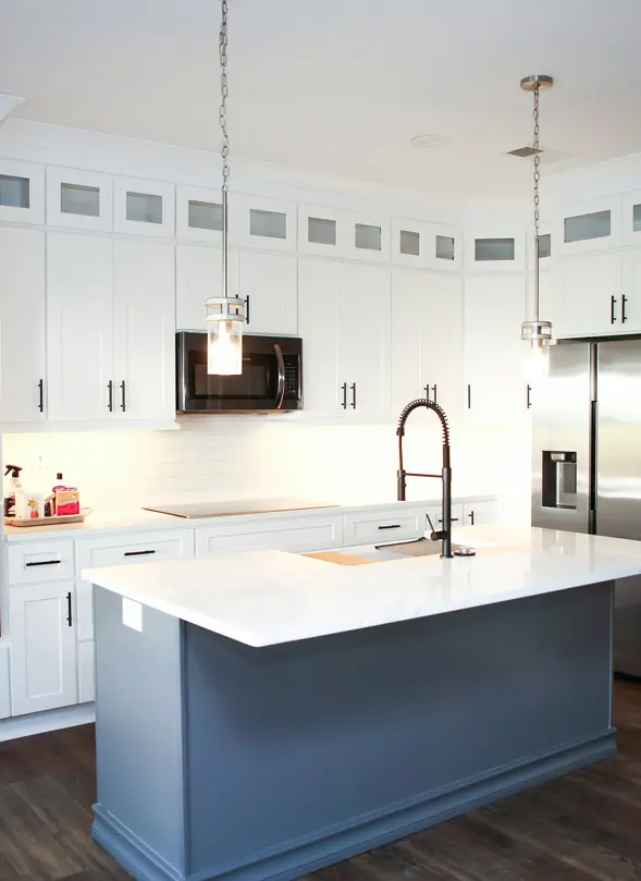 Modern kitchen with white shaker cabinets and a light blue island