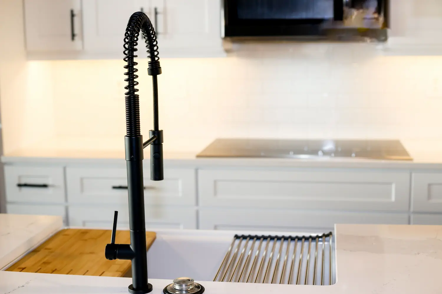 Farmhouse sink with drying rack beside a flush cooktop