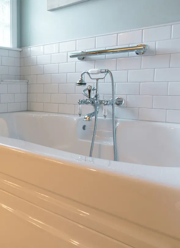 White subway tile bathroom remodel featuring a classic soaking tub with chrome fixtures and a handheld showerhead
