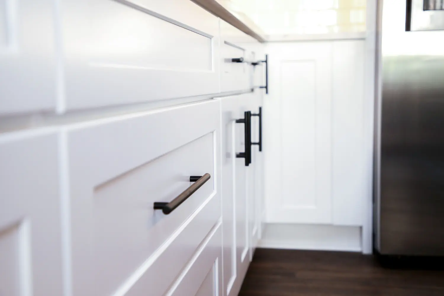 Close view of white shaker cabinet fronts with long black bar pulls
