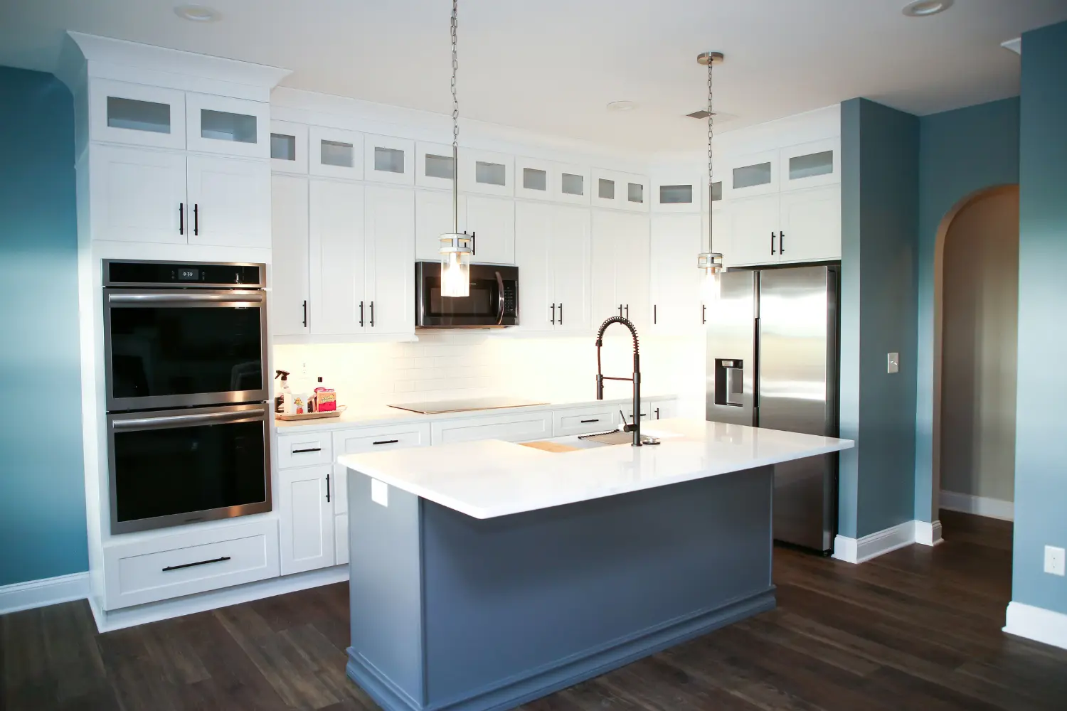 Kitchen with stacked wall ovens, navy island and blue accent wall