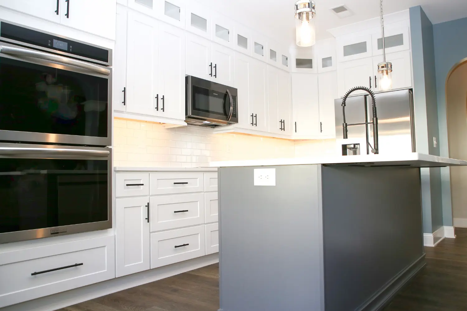 Kitchen with double wall ovens, microwave and a navy quartz-topped island