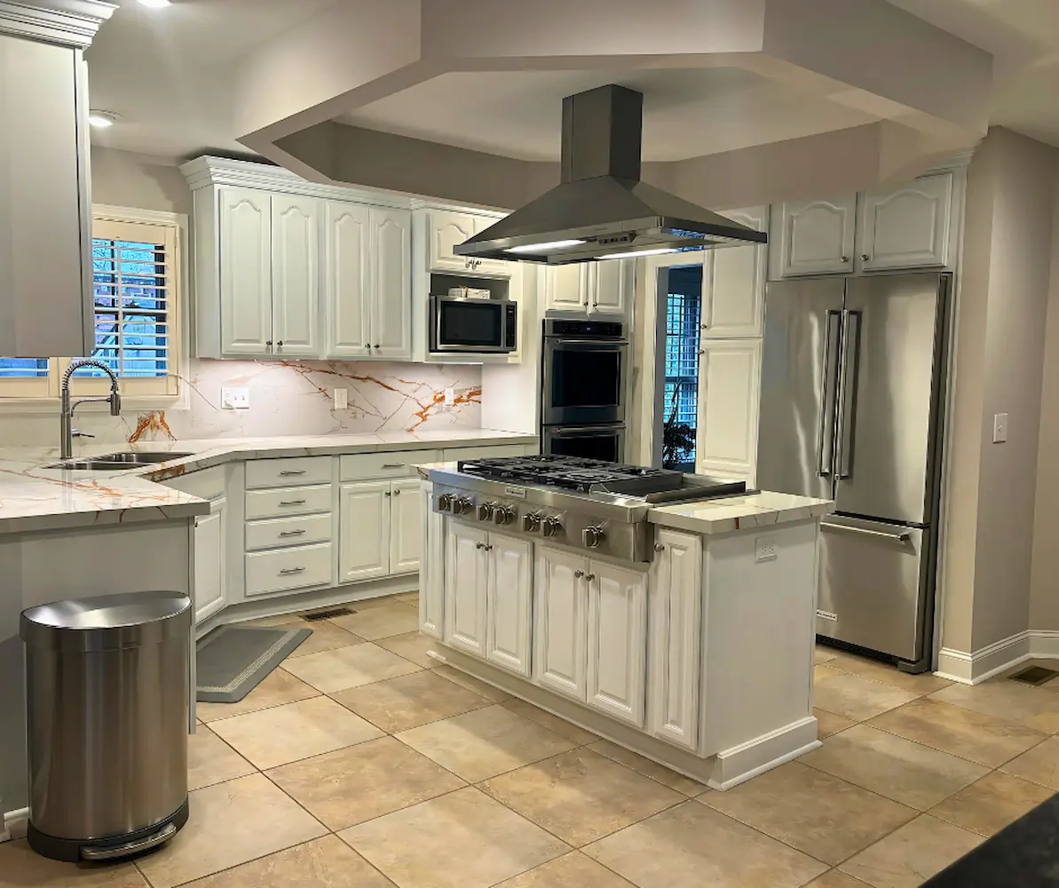 White cabinets with stainless hood over a gas cooktop island