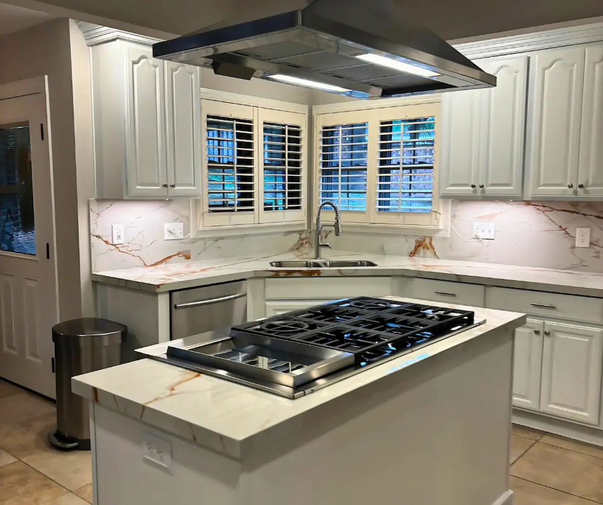 Island cooktop under a stainless hood with plantation shutters