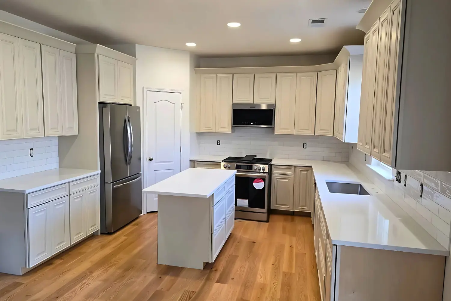 Cream shaker cabinets with a white quartz island on oak flooring