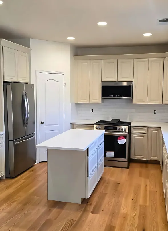 Bright kitchen featuring semi-custom cabinets, sleek stainless steel appliances, and a spacious island, complemented by white countertops and subway tile backsplash