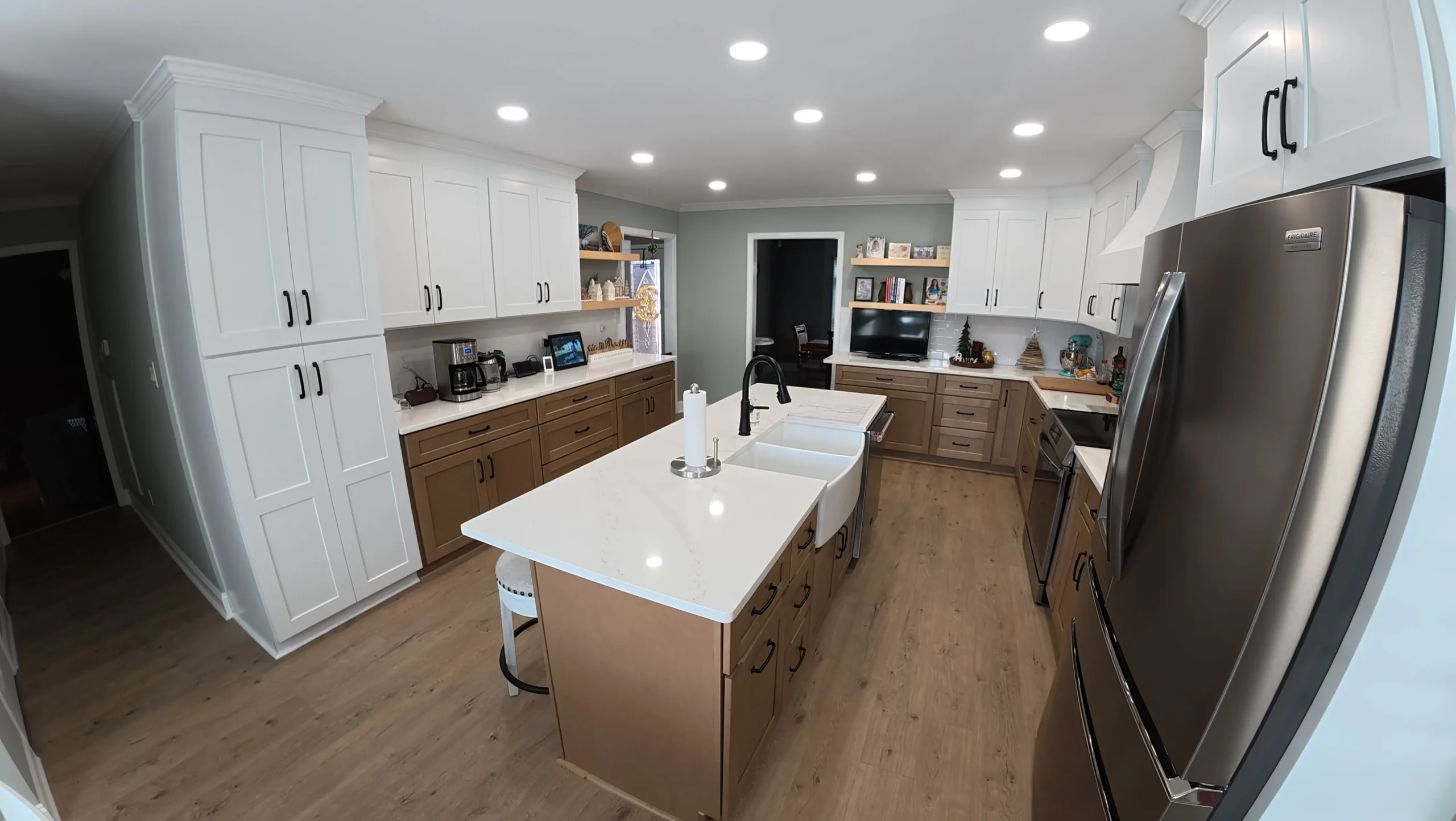 White upper cabinets over walnut lowers with a white quartz island
