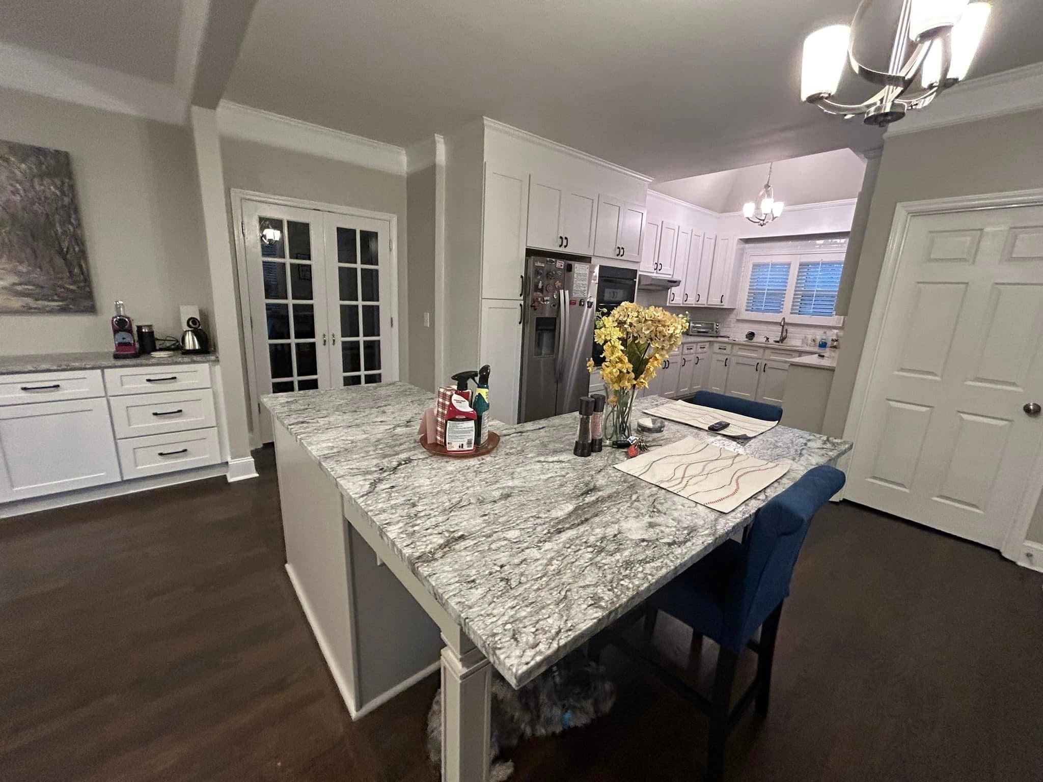 River White granite island under a chandelier with white cabinets