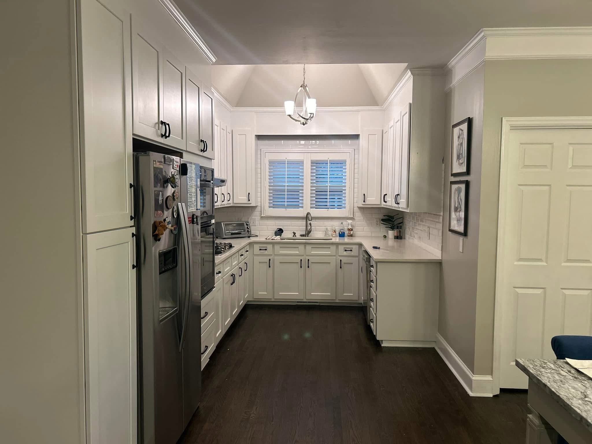 Galley kitchen with white cabinets and dark hardwood flooring
