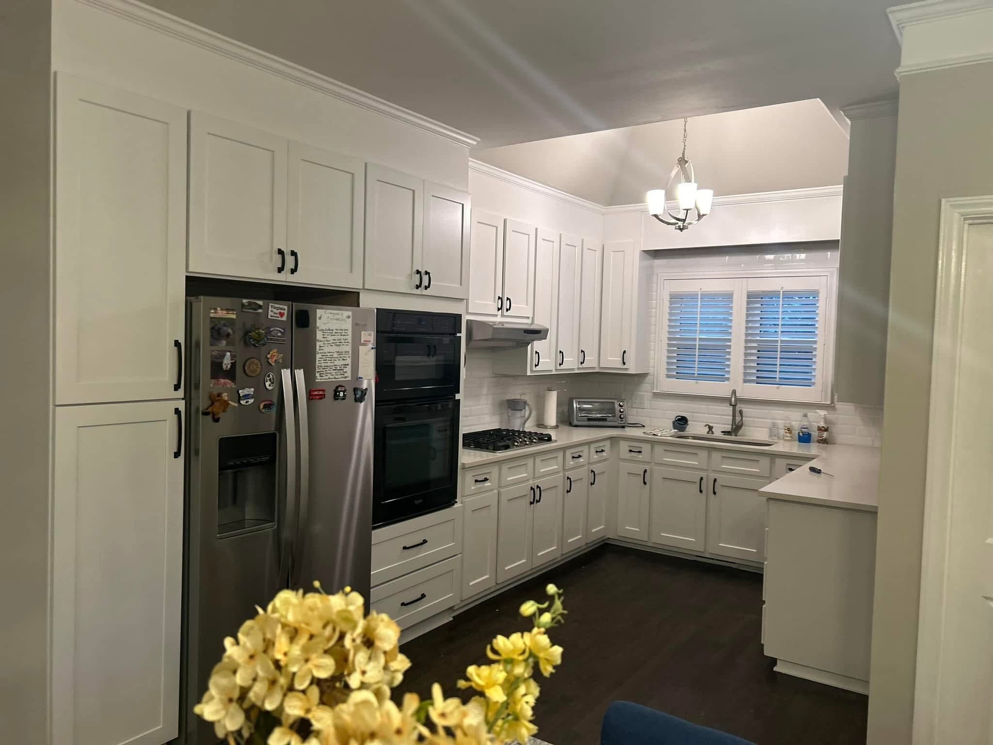 White cabinets and wall ovens beside a granite counter