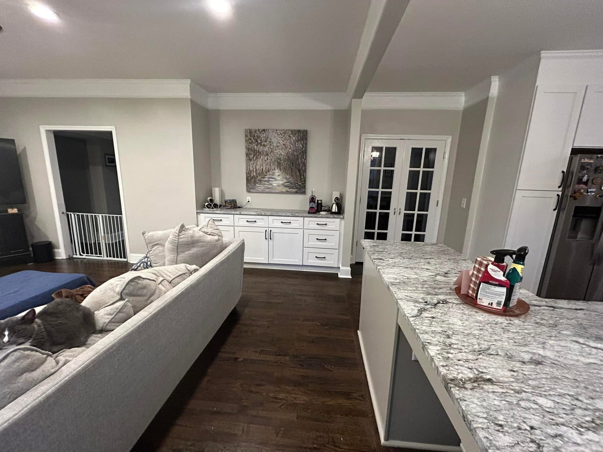 Granite counter overlooking the living room with white cabinetry