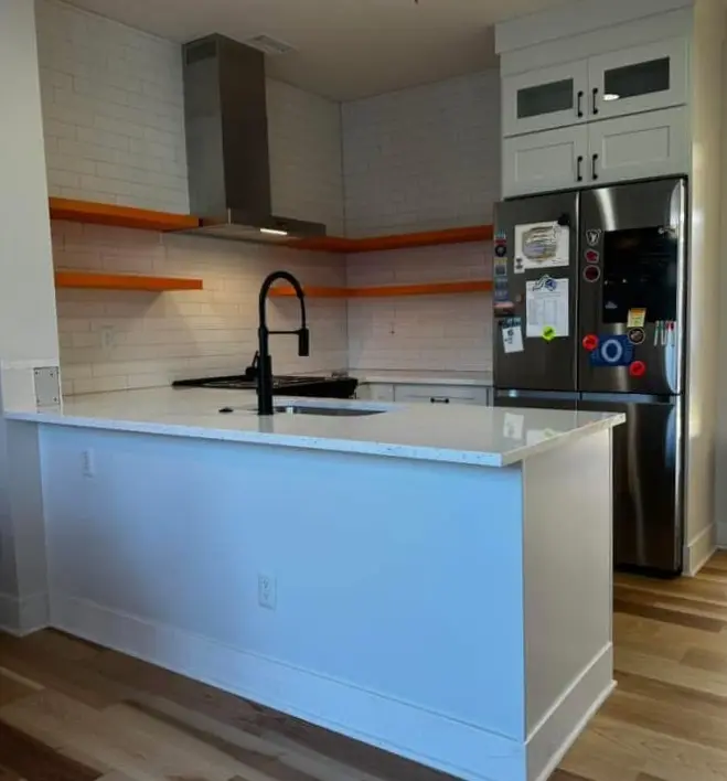 Quartz peninsula with black faucet and orange open shelving