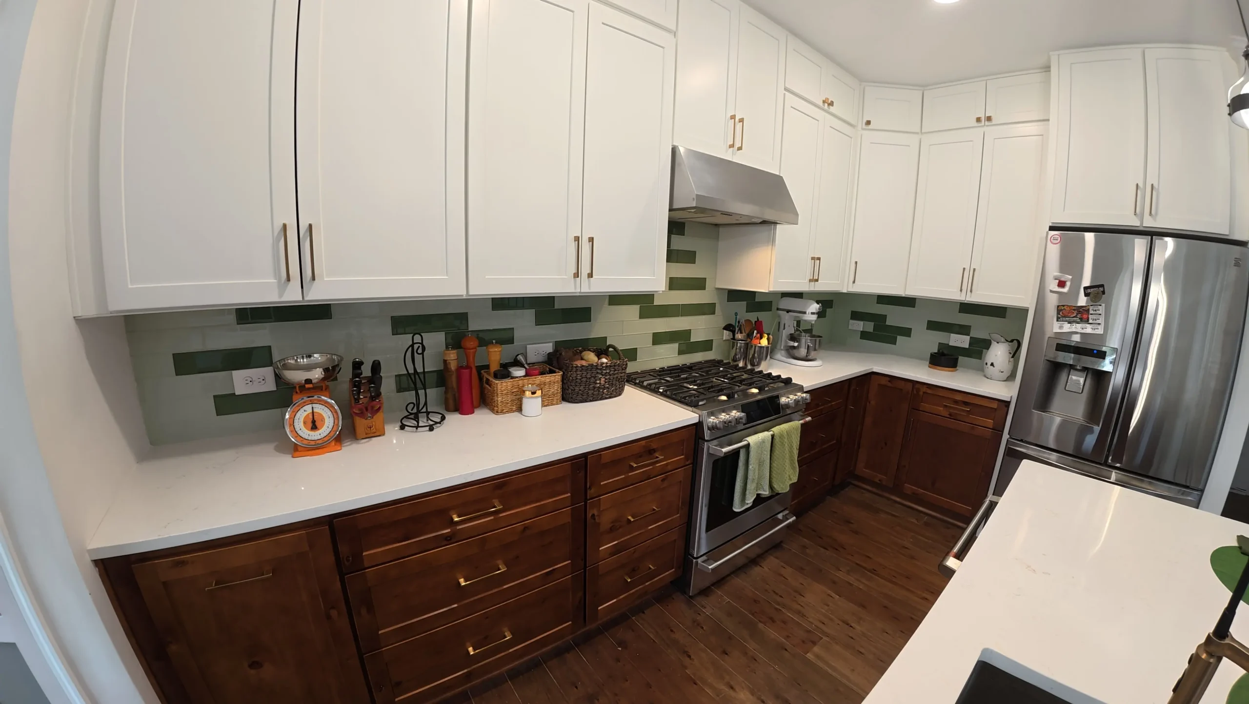 Two-tone kitchen with stainless refrigerator and green tile backsplash