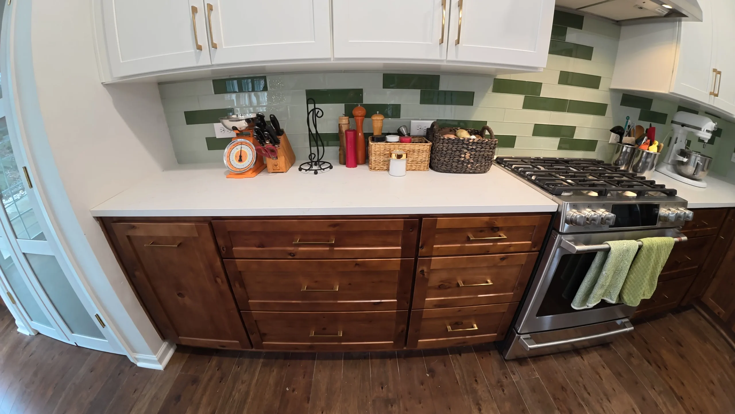 Green stacked tile backsplash above white counters and brown drawers