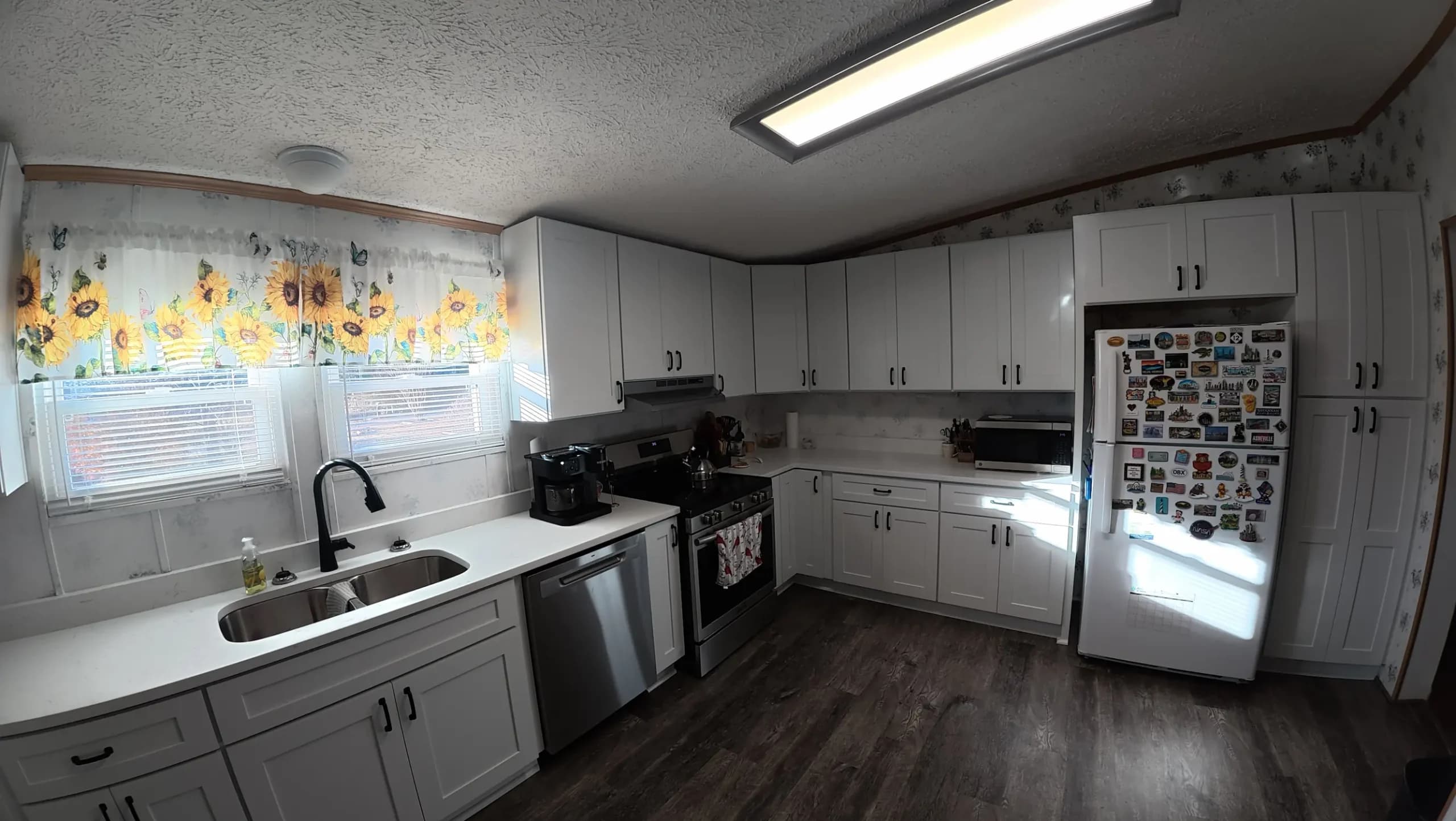 White cabinets and dark vinyl plank flooring with a corner sink