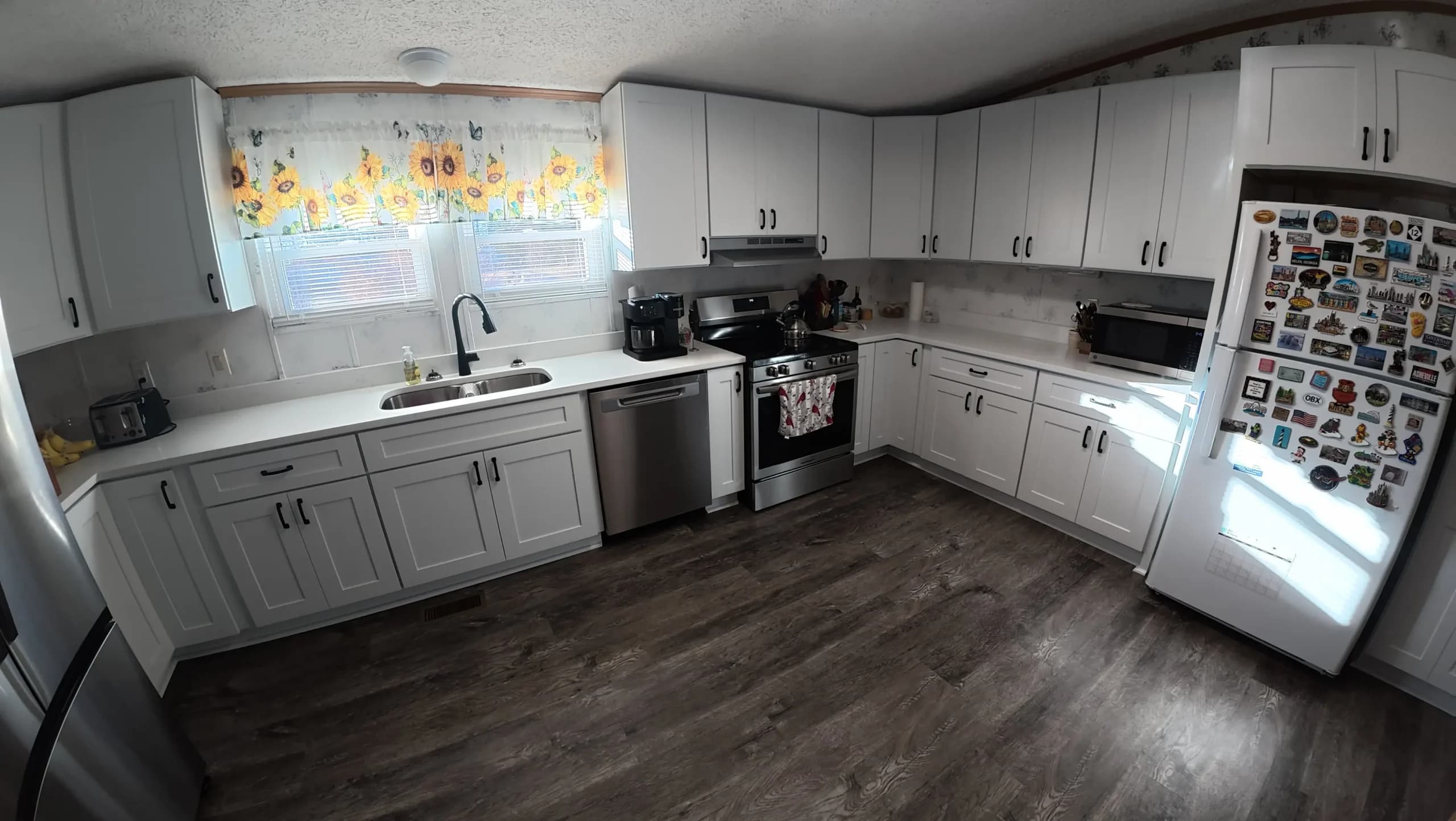 White kitchen with stainless range and dishwasher on dark flooring