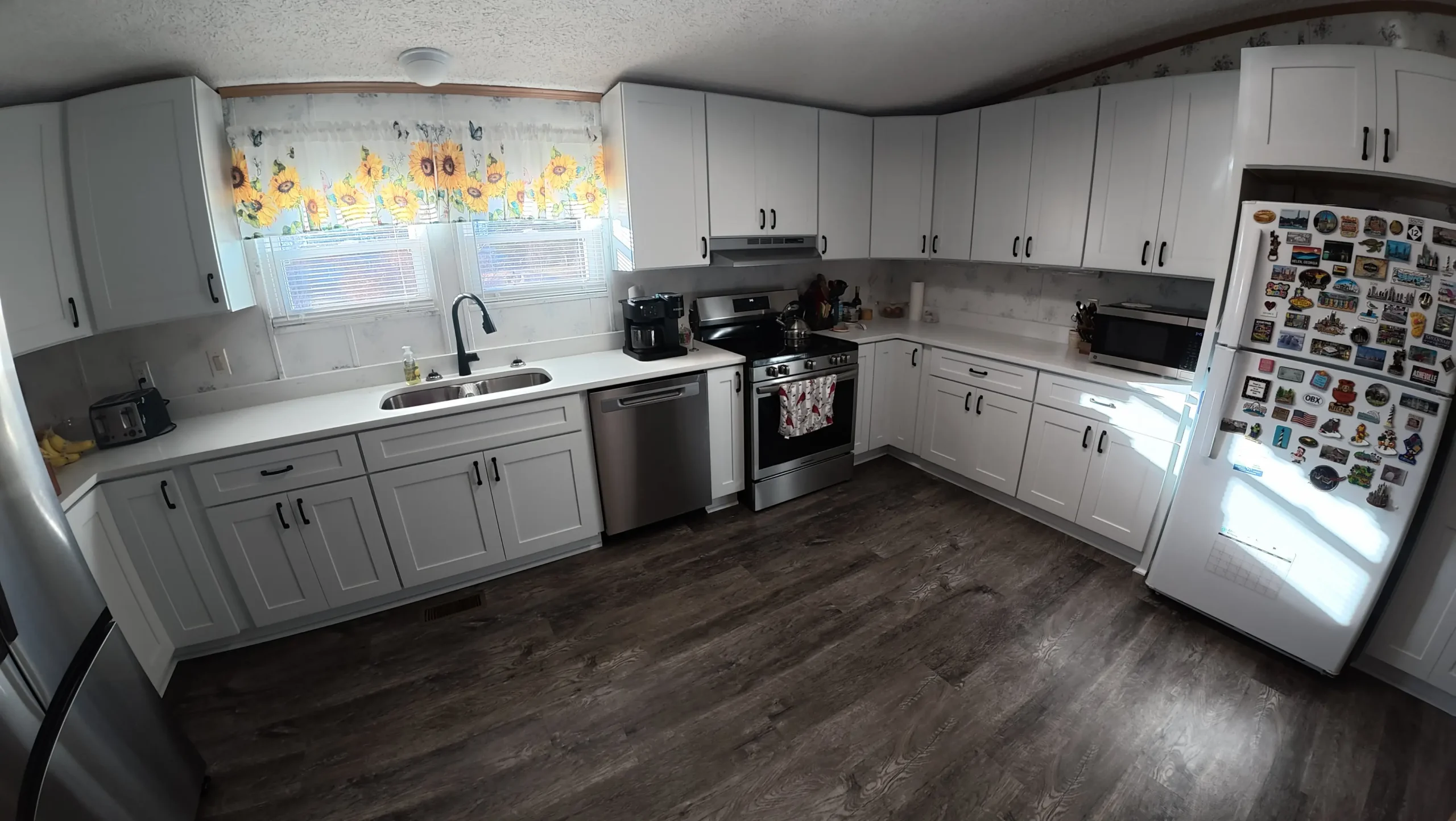 White kitchen with stainless range and dishwasher on dark flooring