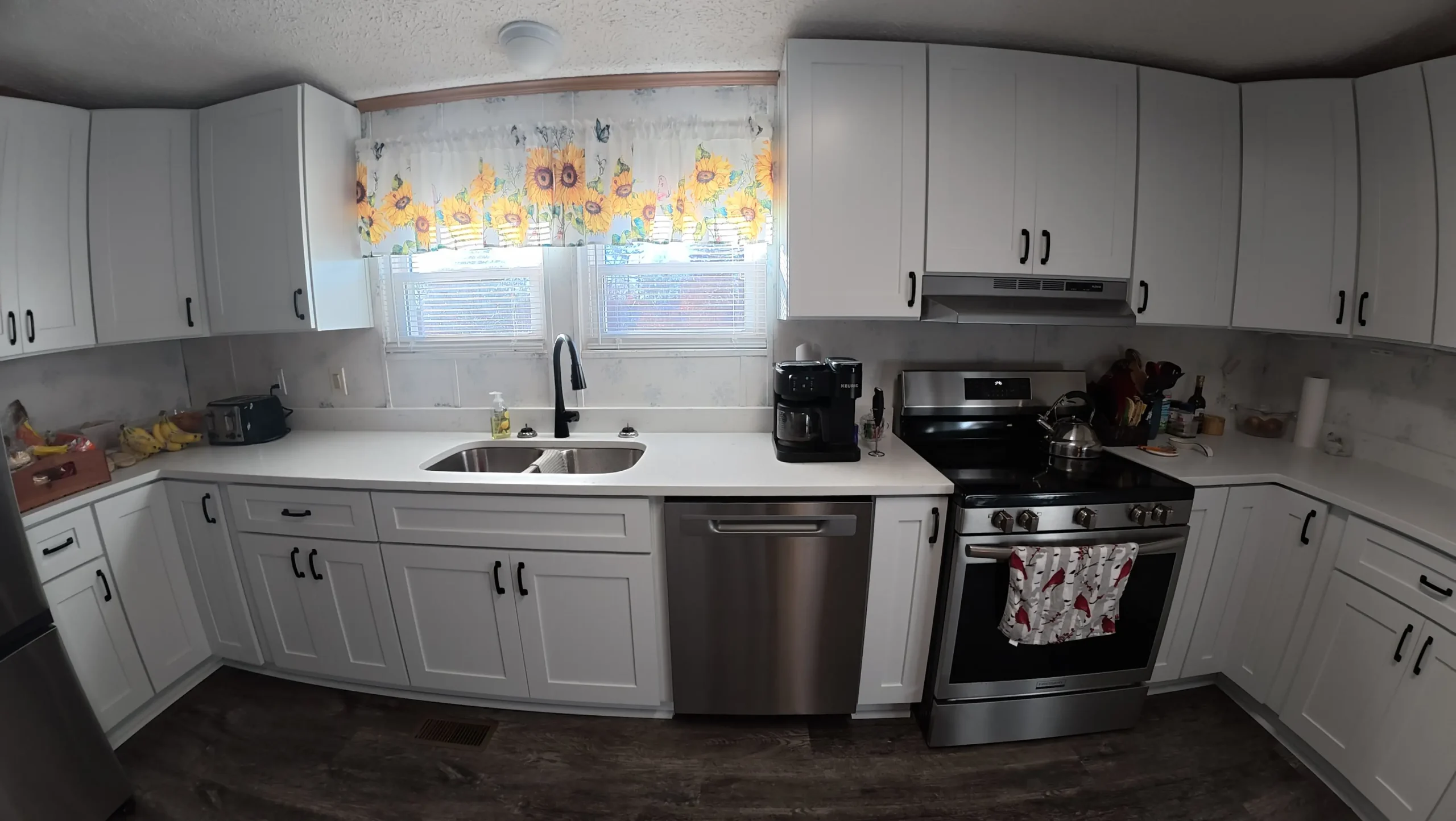 Corner kitchen run with white counters and a double basin sink
