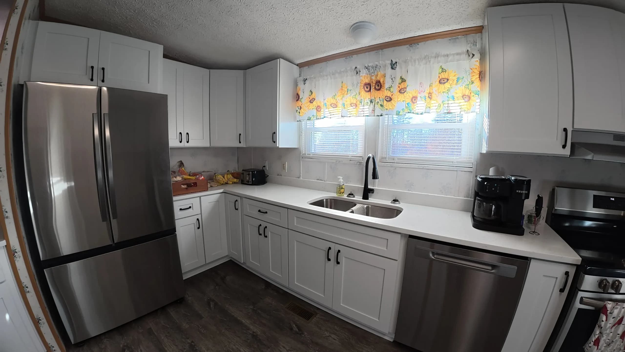 Stainless refrigerator beside white cabinets and white counters